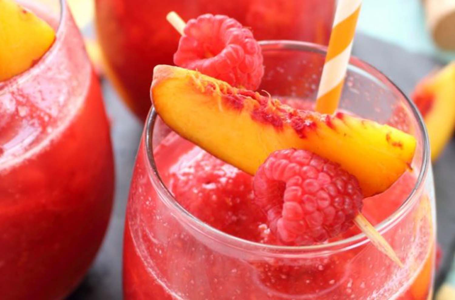glasses of sparkling cocktail with raspberry and peach skewer
