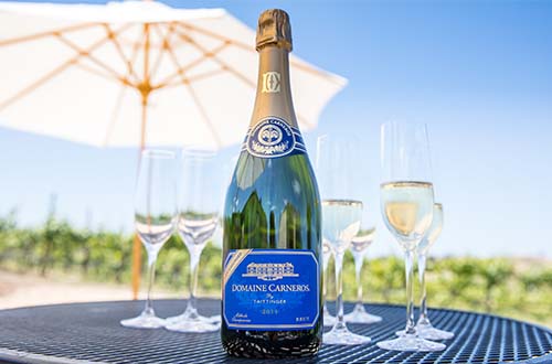 bottle of Late Disgorged Brut on patio table with umbrella