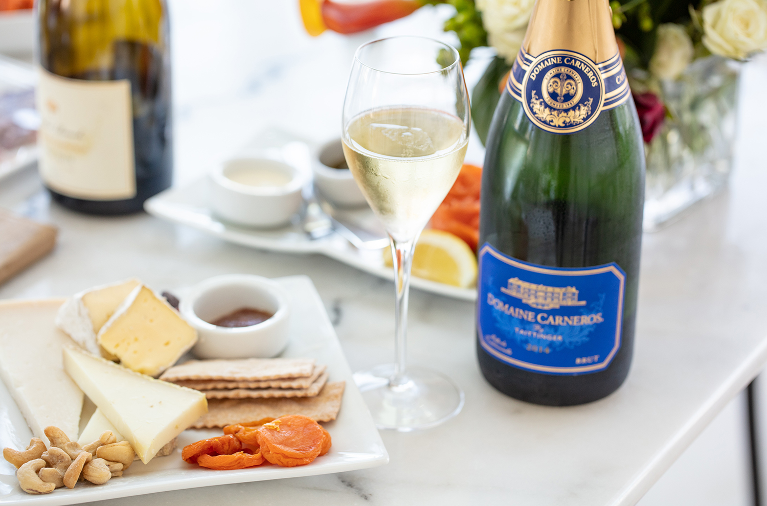 cheese plate with crackers and glass of sparkling wine with Brut bottle