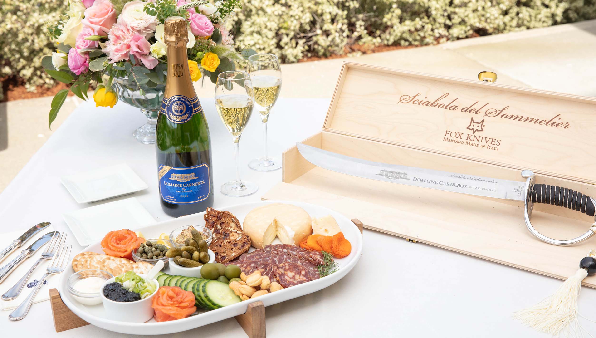 plate of cheese & charcuterie a bottle of sparkling wine and a saber
