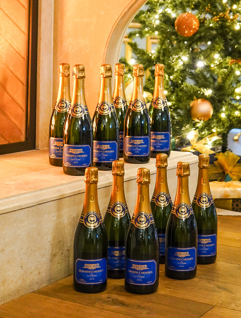 12 bottles of Estate Brut on fireplace in front of Christmas Tree