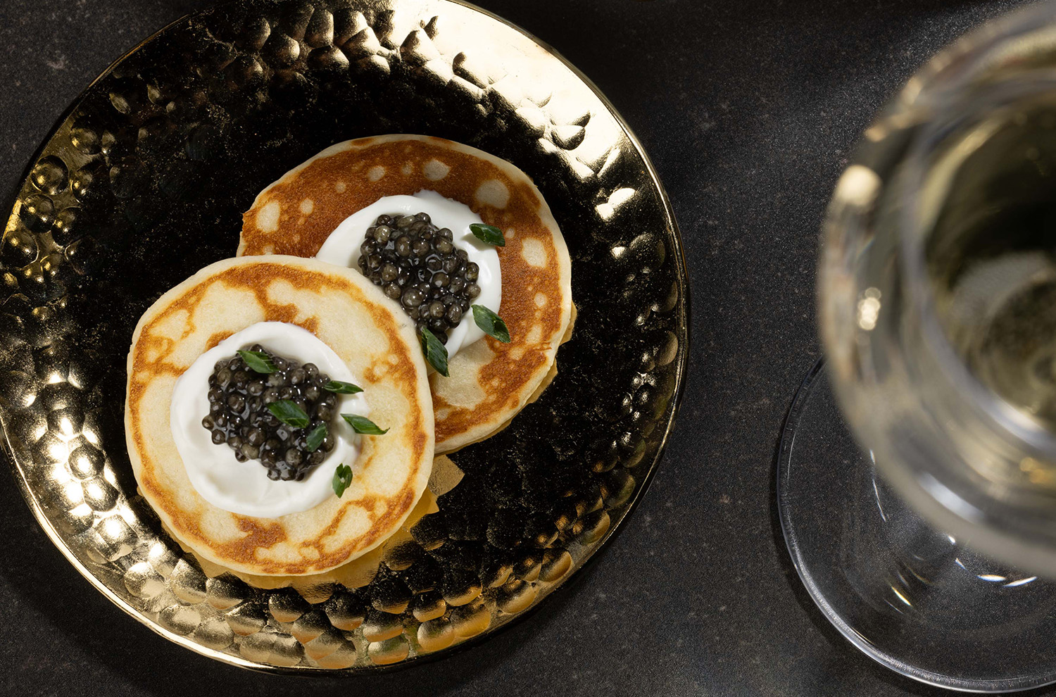 caviar on gold plate with blini and creme friache