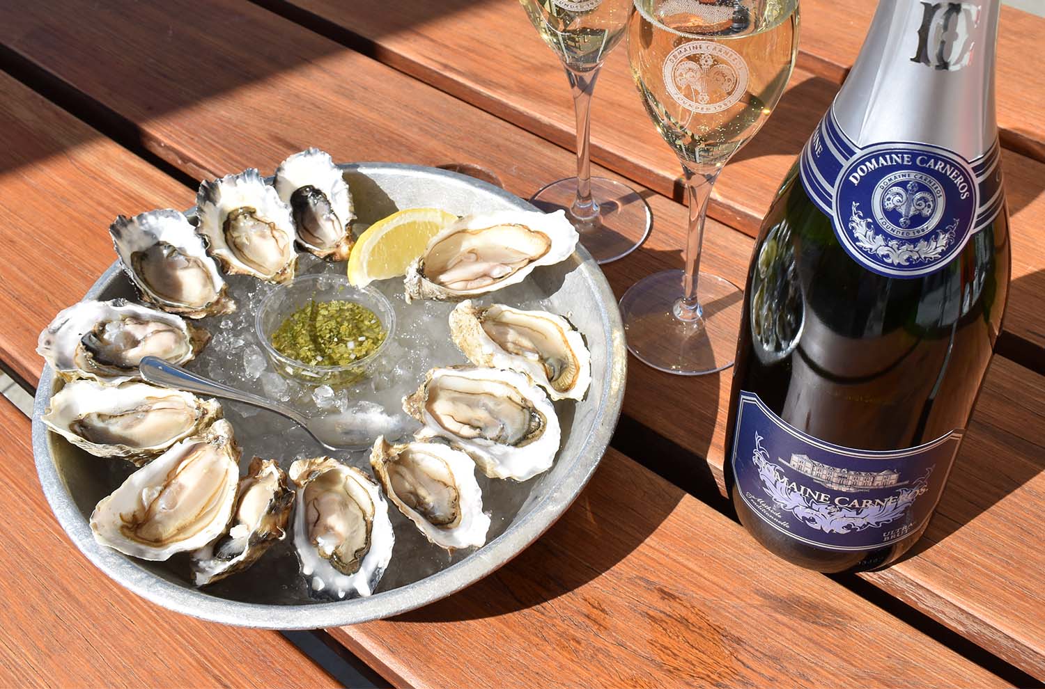 dozen oysters on picnic table with bottle of Ultra Brut