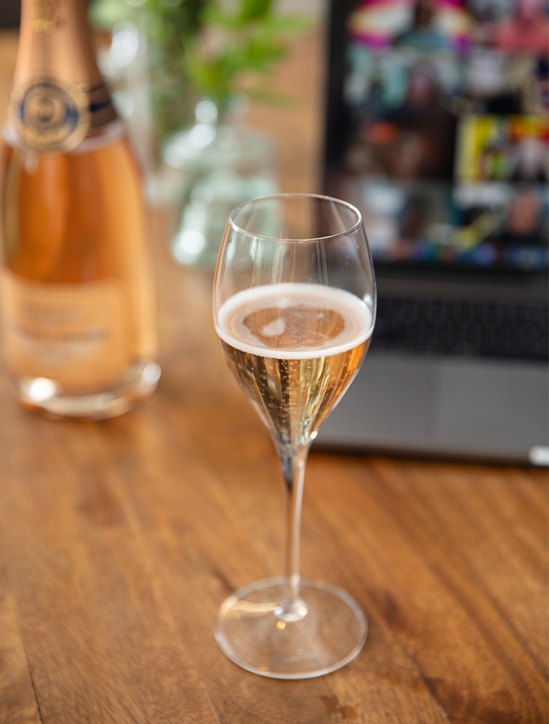 bottle of wine in front of computer with zoom conference on screen